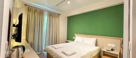A hotel room with a bed, bedside table, and a kettle.