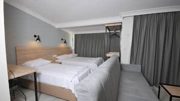Una habitación de hotel moderna con dos camas individuales, un sofá, un escritorio y un armario colgante.