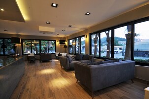 Un moderno vestíbulo de hotel con piso de madera, sofás grises y amplias ventanas que dan a la calle.