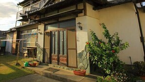 A traditional Japanese house with a tiled roof, sliding doors, and a small garden with potted plants. - Minshuku Urashima (Minamiizu)