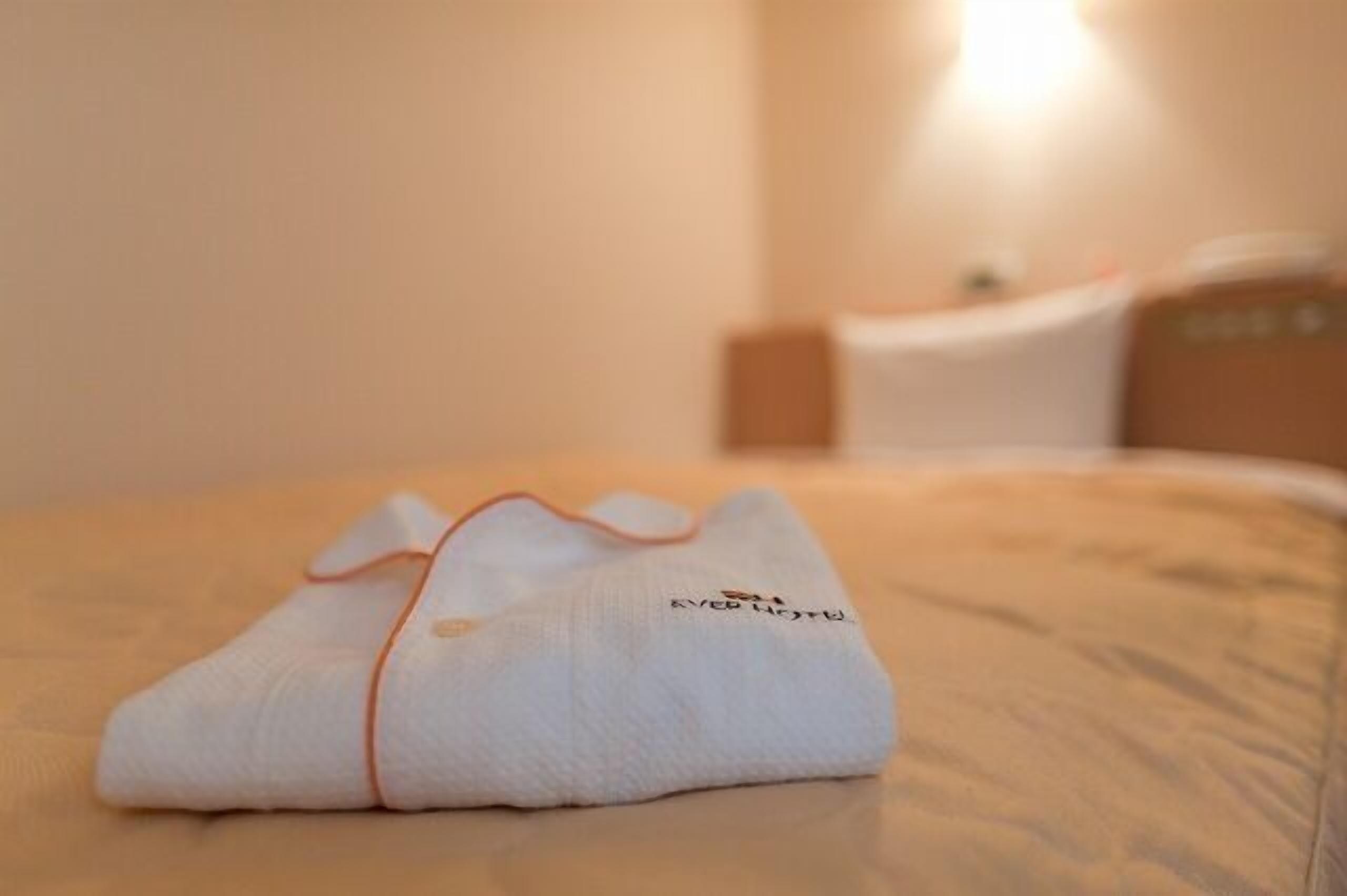 A neatly folded towel with a logo on a bed in a hotel room.