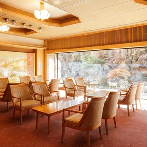 Ein Hotelzimmer mit großem Fenster, Holzmöbeln und Blick auf einen Garten.