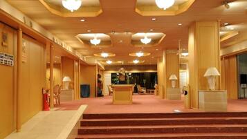 A hotel lobby with a reception desk, a staircase, and a carpeted floor.