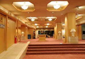Eine Hotelhalle mit einer Rezeption, einer Treppe und einem Teppichboden.