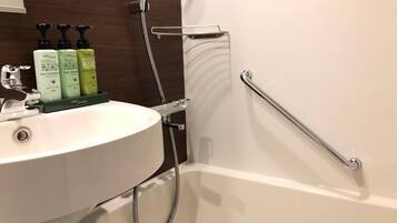 A bathroom with a white sink, a handheld showerhead, and a grab bar.