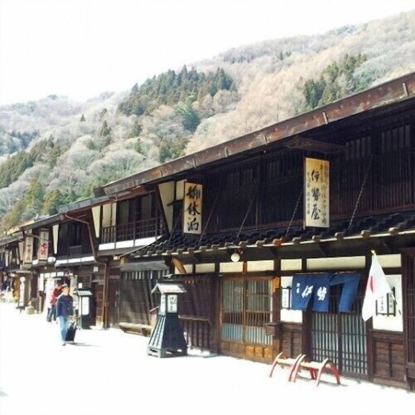 Een traditioneel Japans gebouw met houten architectuur, meerdere borden en een bergachtige achtergrond.