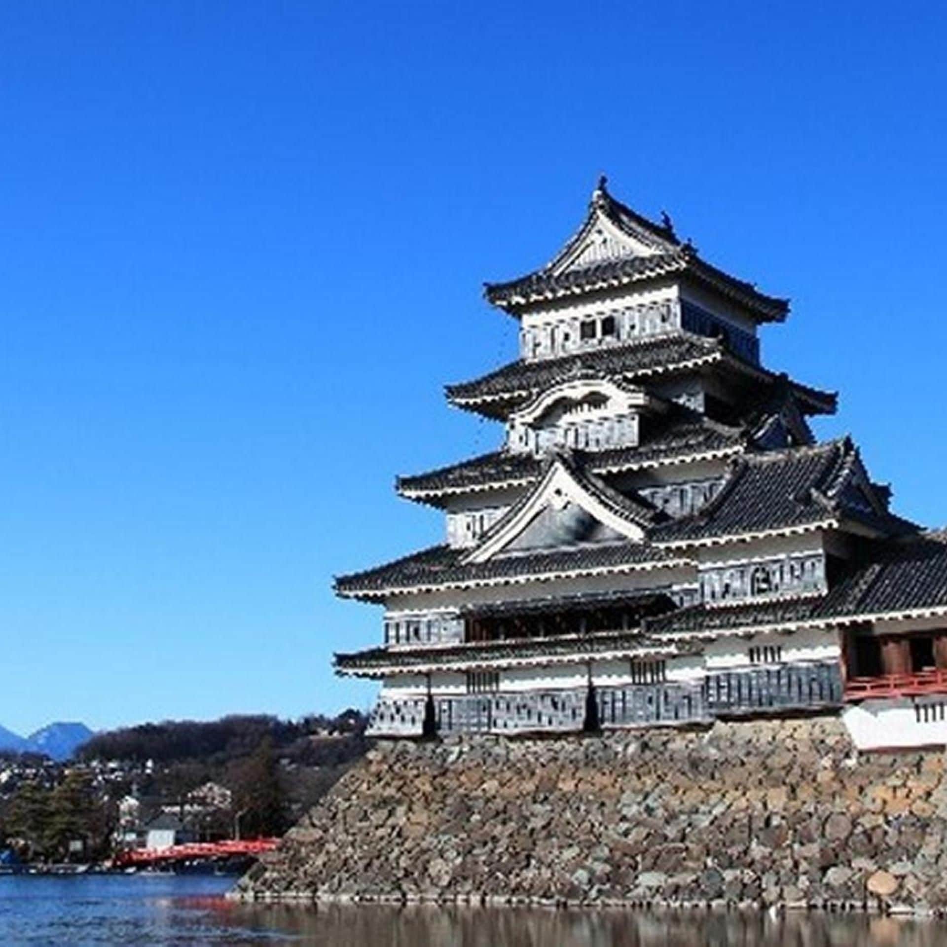 A traditional Japanese castle with multiple tiers, situated by a body of water.