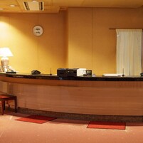 A reception desk with a clock, a telephone, and a coffee machine.