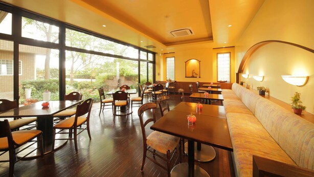 A restaurant with wooden tables and chairs, a long bench, and large windows offering a view of the outdoors. - Petit Hotel Clanvert (Hagi)
