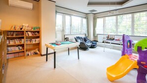 A room with a pool table, bookshelves, a slide, and a table with chairs. - Petit Hotel Clanvert (Hagi)