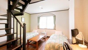 A room with a wooden staircase, two single beds, a small table, a desk with a lamp, and a window with curtains. - Petit Hotel Clanvert (Hagi)