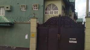 Un immeuble clos, doté d’une façade verdoyante, d’une enseigne indiquant « Centre d’affaires » et d’une porte d’entrée grillagée.