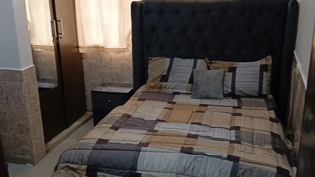 Une chambre à coucher avec un lit, des rideaux, une table de chevet et une porte.