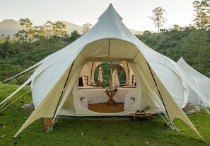 A dome-shaped tent with a bed inside, surrounded by a grassy area and trees. - Kinkara Luxury Retreat (El General)