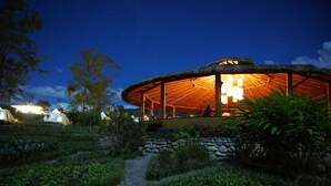 A thatched-roof structure with a central light fixture, surrounded by a garden path and greenery. - Kinkara Luxury Retreat (El General)