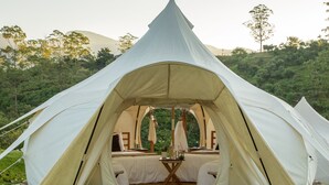 A dome-shaped tent with a bed and a small table in the center, surrounded by greenery. - Kinkara Luxury Retreat (El General)