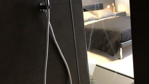 Un baño moderno con ducha, cama y mesita de noche.
