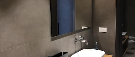 Un baño moderno con un espejo grande, un lavabo blanco y un mueble de tocador de madera.