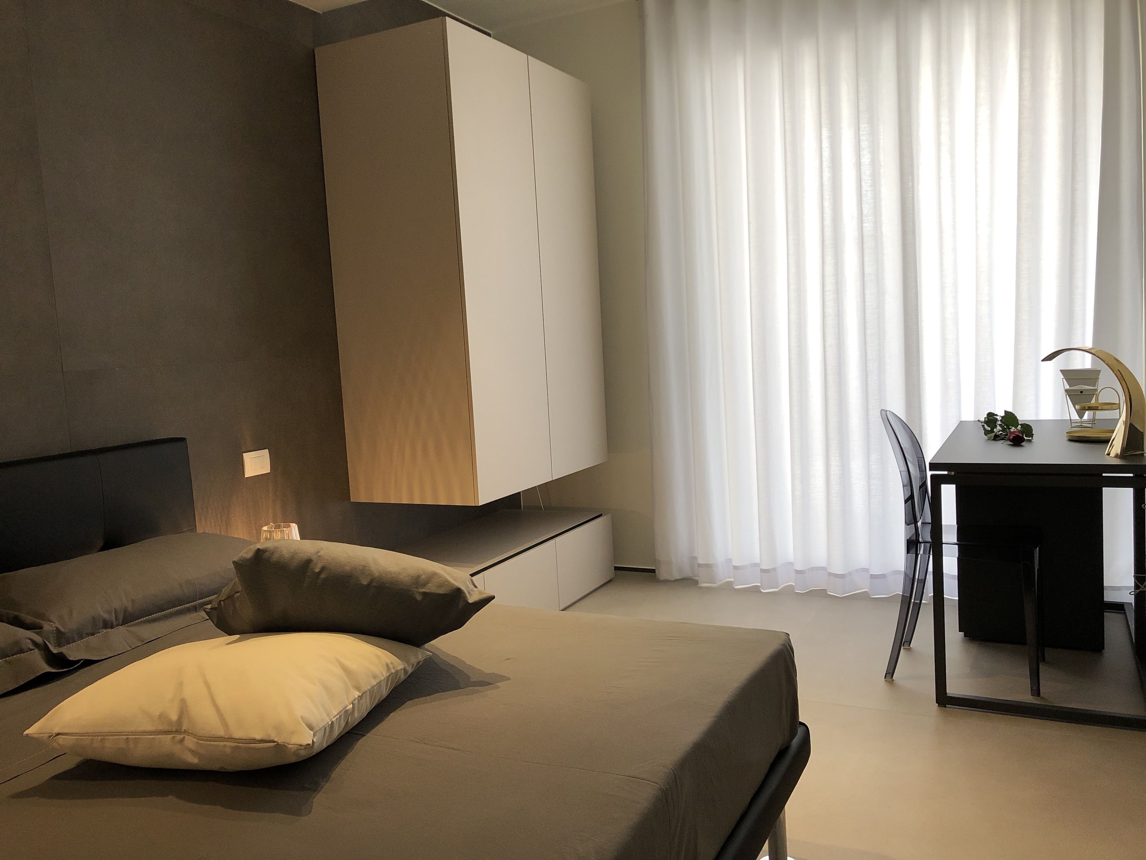 A modern bedroom with a bed, a desk, and a wardrobe.