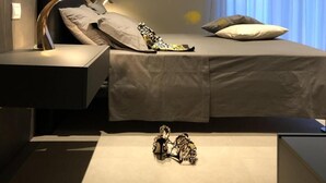 Un dormitorio moderno con cama, mesitas de noche y un objeto decorativo en el suelo.