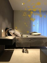 Una camera da letto moderna con un letto, comodini e un oggetto decorativo a terra.