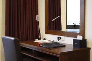 A hotel room with a wooden desk, a laptop, a microphone, a tissue box, and a window with curtains. - 7S West Lake Home Hotel & Spa (Hà Nội)
