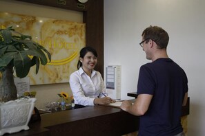 A hotel reception desk with a receptionist and a guest. - 7S West Lake Home Hotel & Spa (Hà Nội)