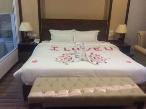 A hotel room with a bed featuring a towel art arrangement spelling "I LOVE YOU" and a tufted bench in front. - 7S West Lake Home Hotel & Spa (Hà Nội)
