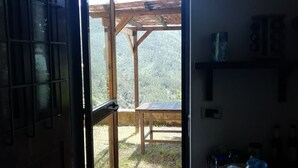 Una puerta abierta que da a un patio exterior con una pérgola de madera, un sendero de piedra y una mesa.