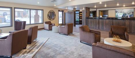 A modern lobby with sofas, a coffee table, and a reception area with a counter.