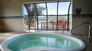 Un área de piscina con vistas a una terraza y sillas, un letrero que indica ducharse antes y después de usar las piscinas y jacuzzis, y una pared de azulejos.