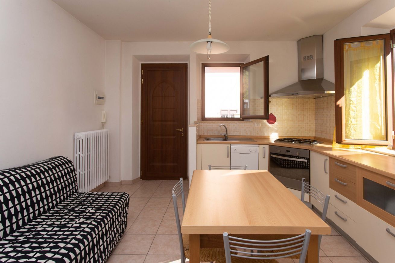 Una cucina funzionale con tavolo, sedie, divano e una finestra.