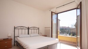 A bedroom with a bed, a nightstand, a lamp, and a view of a balcony. - N032 - Numana, new three-room apartment with terrace on the left (Numana)