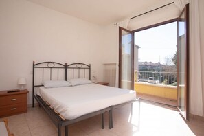 A bedroom with a bed, a nightstand, a lamp, and a view of a balcony. - N032 - Numana, new three-room apartment with terrace on the left (Numana)