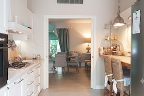 Una cocina moderna con armarios blancos, un comedor con mesa y sillas, y vistas a una sala de estar.