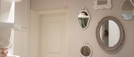 A bathroom with a white door, a sink with a blue vase, and three mirrors on the wall.