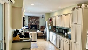 A kitchen with white cabinets, a brick wall, a refrigerator, and a microwave. - Southold, NY- Heart of North Fork Wine Country and Minutes From The Beach (Southold)