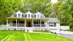 A two-story house with a front porch, a covered entryway, and a small front yard with potted plants. - Southold, NY- Heart of North Fork Wine Country and Minutes From The Beach (Southold)