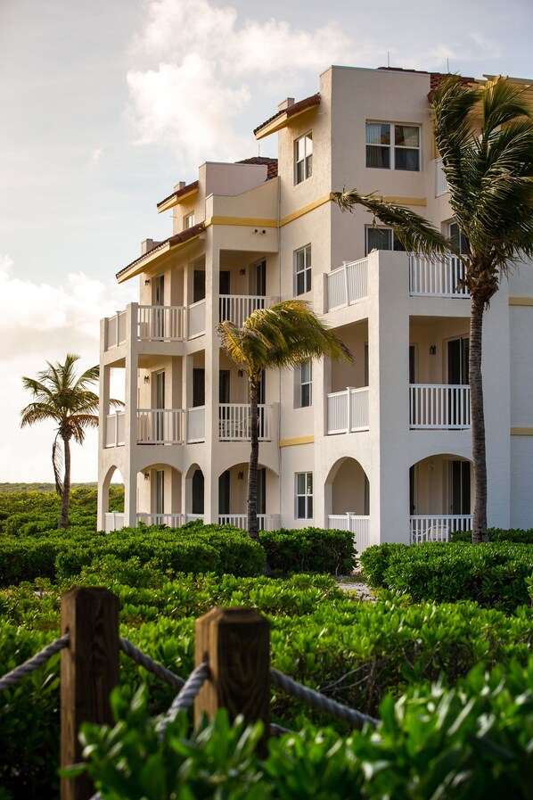 A multi-story hotel with balconies, arched windows, and a view of the surrounding greenery.