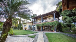 A two-story building with a stone pathway leading to a covered patio area. - Beautiful Chalet in El Caimo (El Caimo)