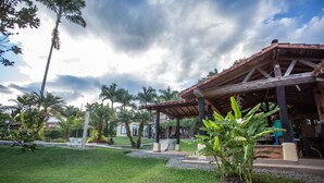 A covered outdoor area with a wooden roof, surrounded by greenery and palm trees. - Beautiful Chalet in El Caimo (El Caimo)