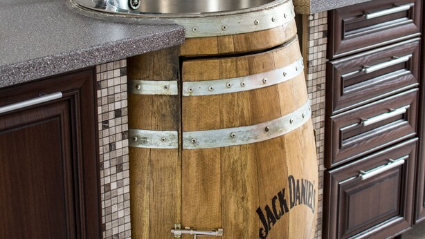 Una cocina con un lavamanos de barril de madera, un grifo de acero inoxidable y un salpicadero de azulejos.