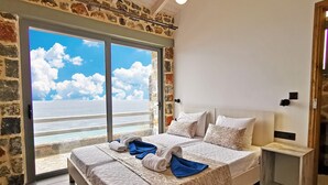 Ein Schlafzimmer mit einer großen Schiebeglasdoor zum Balkon mit Meerblick.