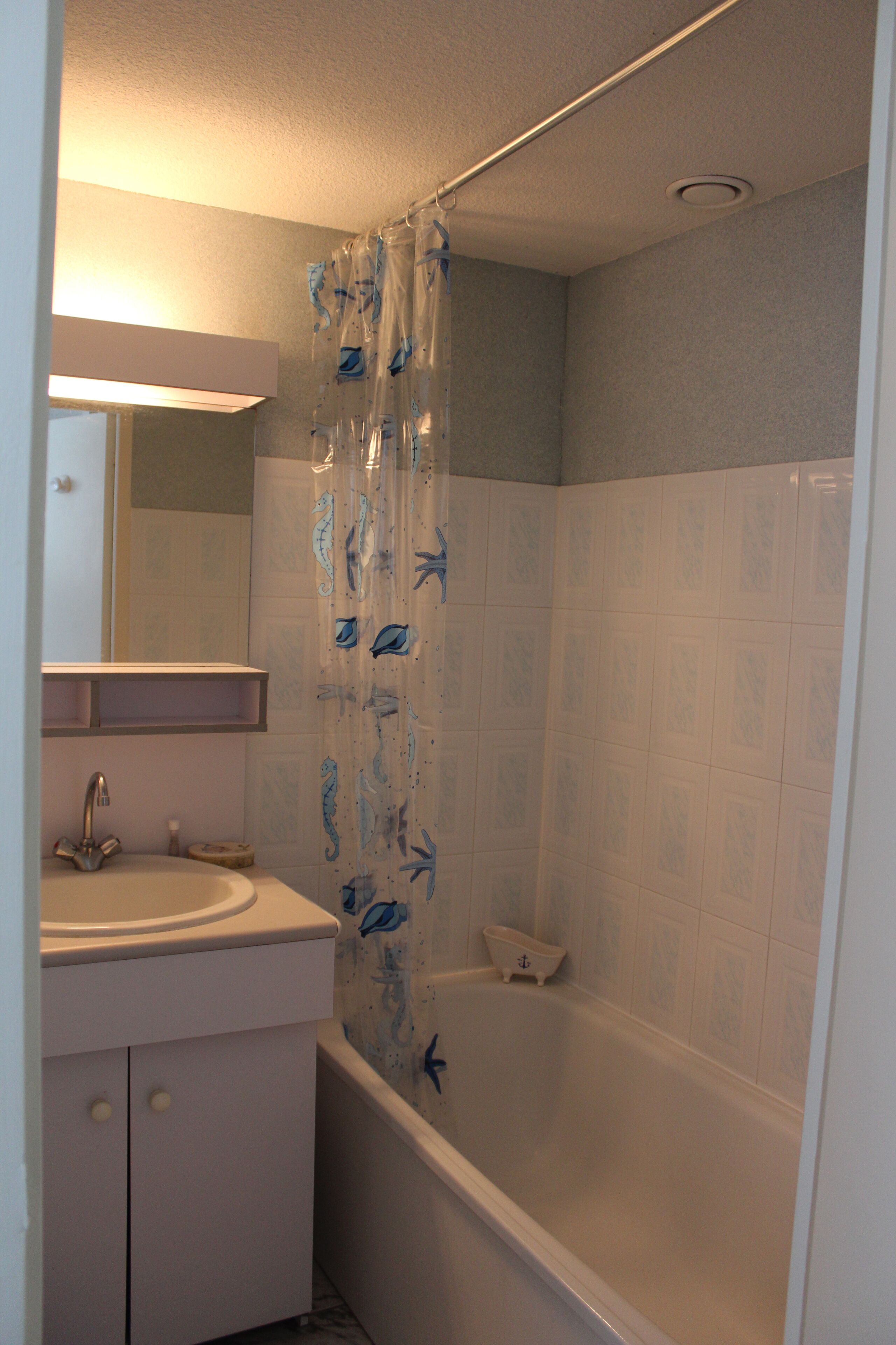 A bathroom with a bathtub, a sink, and a mirror.