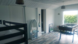 Een kamer met een bed, een tafelvoetbaltafel en een raam met uitzicht op groen.