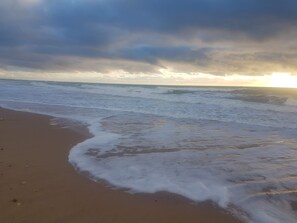 A beach with waves gently lapping at the shore under a cloudy sky. - Maison Grand Village, Meublé de Tourisme 2 * Registration N° : 1748500005992 (Le Grand-Village-Plage)