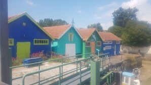 Een rij kleurrijke houten gebouwen met een groene trap die naar een steiger leidt.
