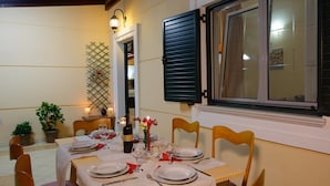 A dining table set for four with plates, cutlery, and glasses. There is a bottle of wine and a candle on the table. - Villa AnnaMaria (Minoa Pediada)