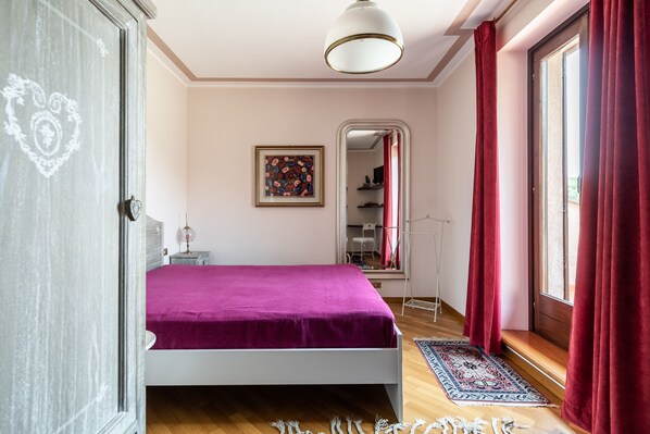 A bedroom with a bed, a bedside table, a mirror, and a window with curtains. - Beautiful villa with pool surrounded by nature near Golf and Tennis courts (Beregazzo con Figliaro (Co))