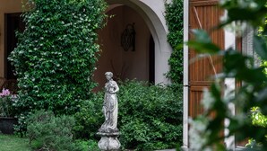 A building with a tiled roof, an arched doorway, and a statue in the garden. - Beautiful villa with pool surrounded by nature near Golf and Tennis courts (Beregazzo con Figliaro (Co))